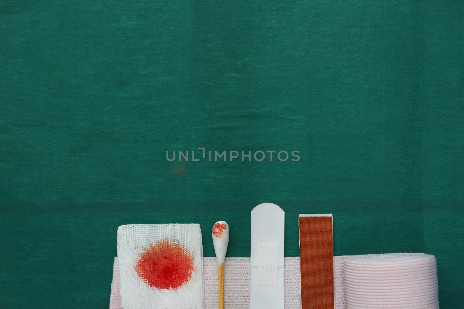 half tools includes plaster,swab,blood gauze and roll gauze on green surgical dress for clean wound with copy space