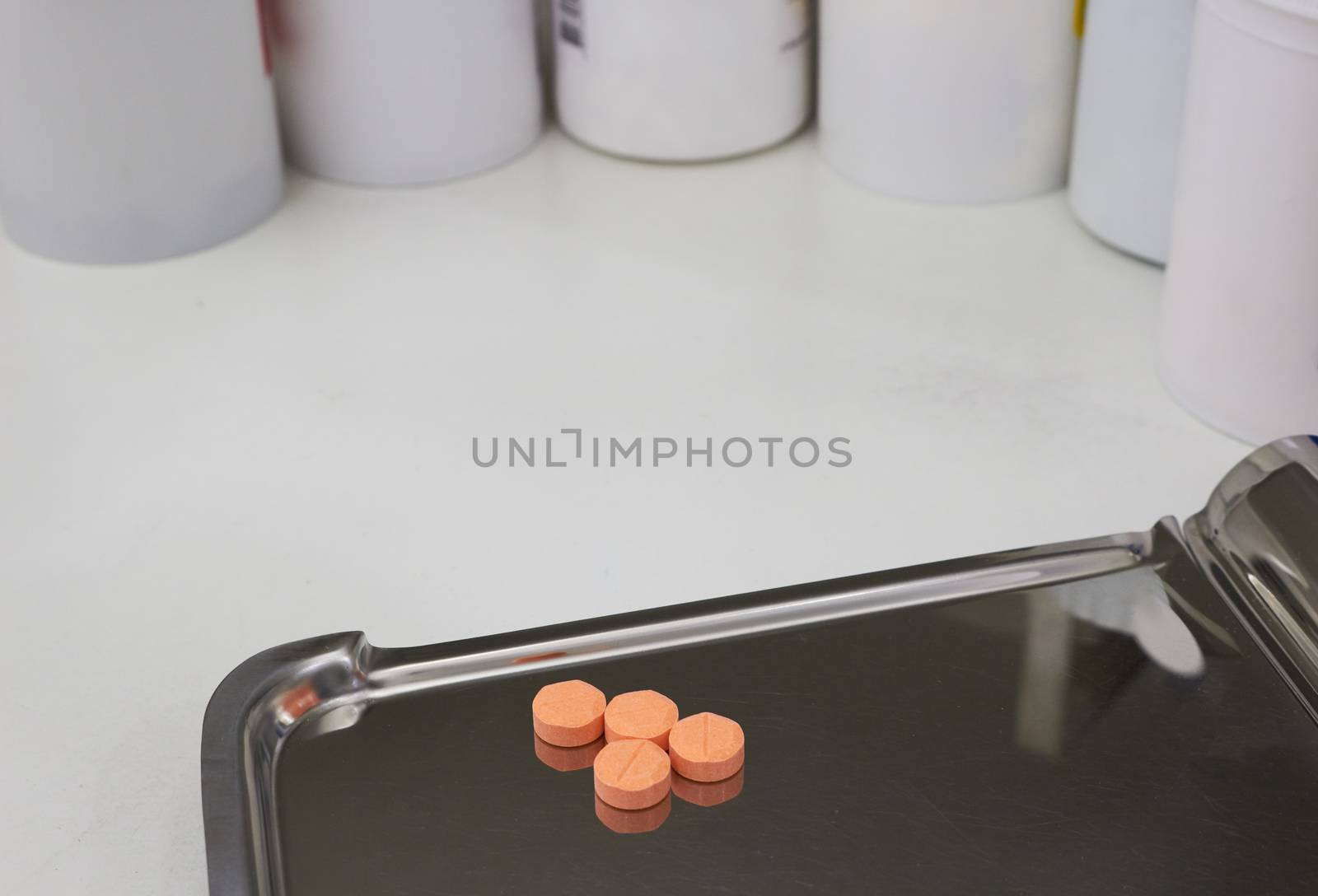 four orange medical tablets on half counting drug tray for drugstore