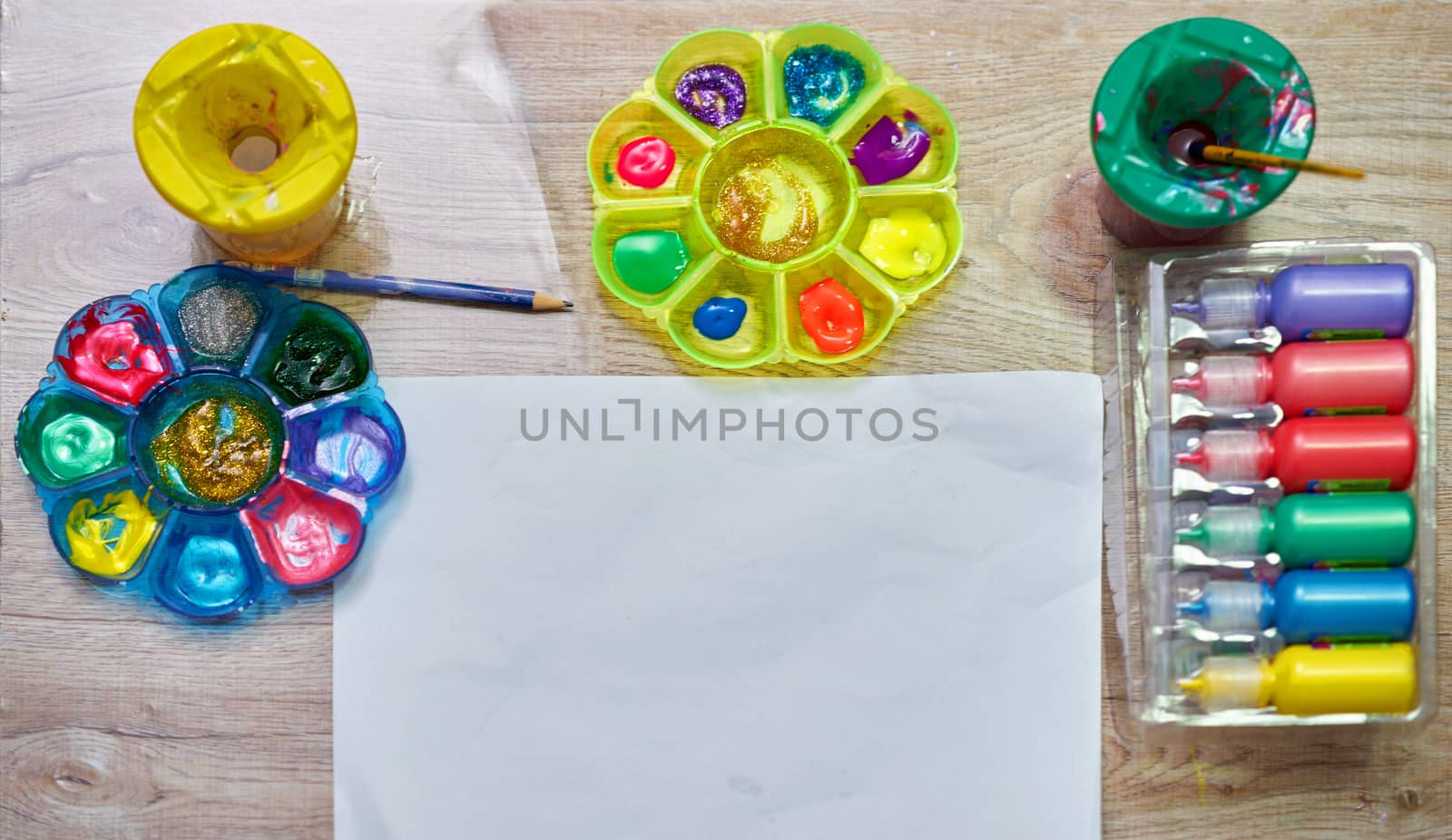 mock up paper and color palettes ,brushes and bottle of water color on wood table