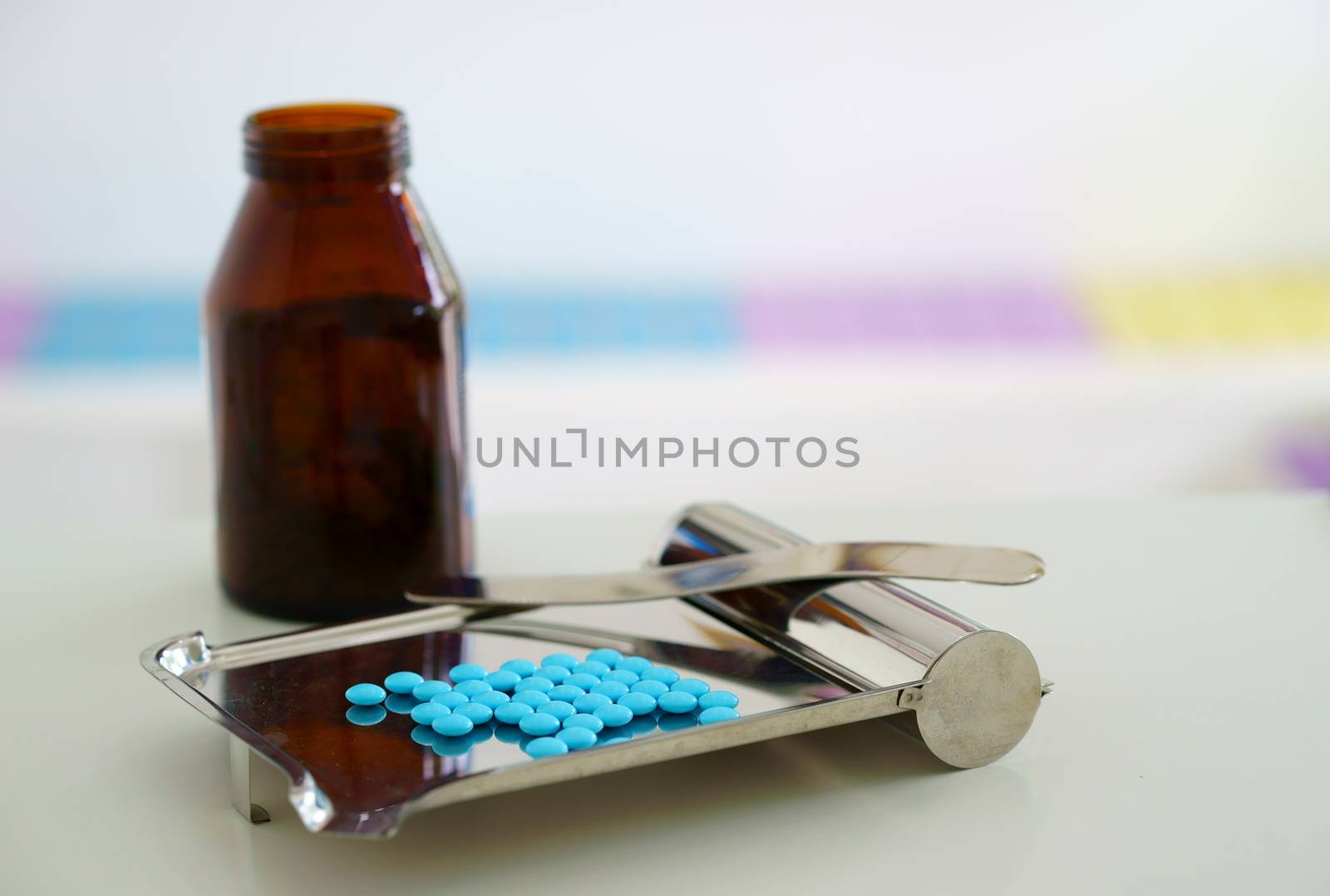 pills counting tray with spatula and round coated medicine tablets and jar on blur background with copy space