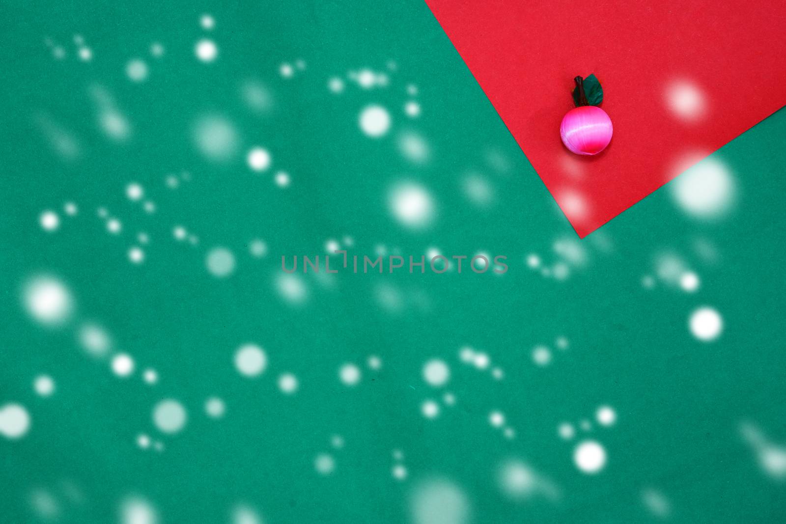 Pink fruit on red and green background with copy space for new year and christmas time with snow fall