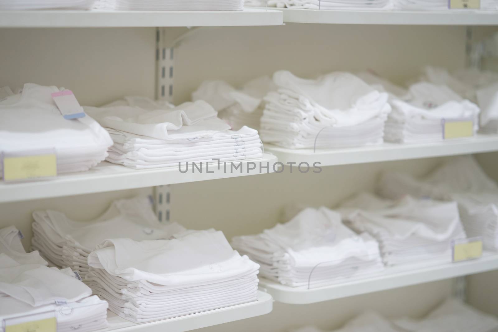 White clothes in shelves for sale by VacharapongW