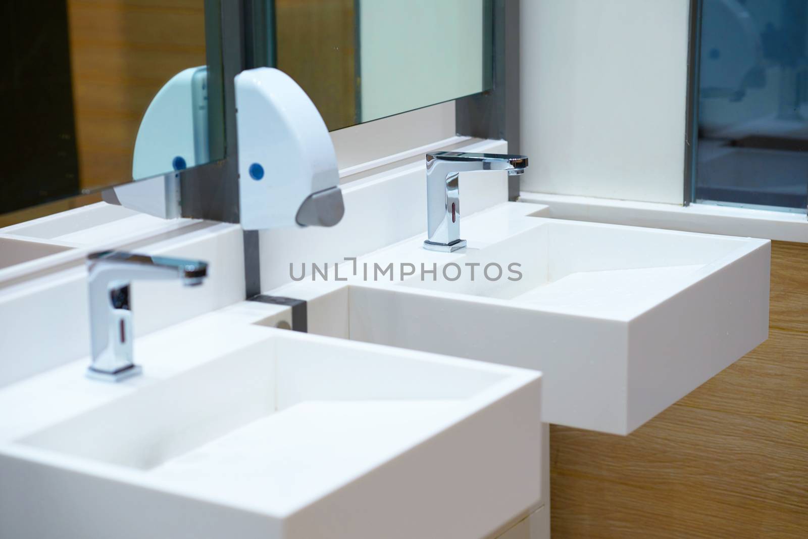 White ceramic sink and water tap with soap dispenser in bath room or toilet
