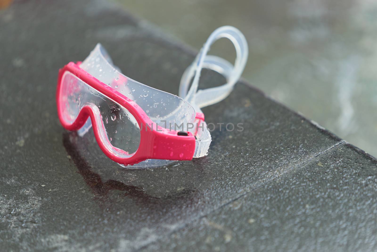 Water swimming goggles on pool side