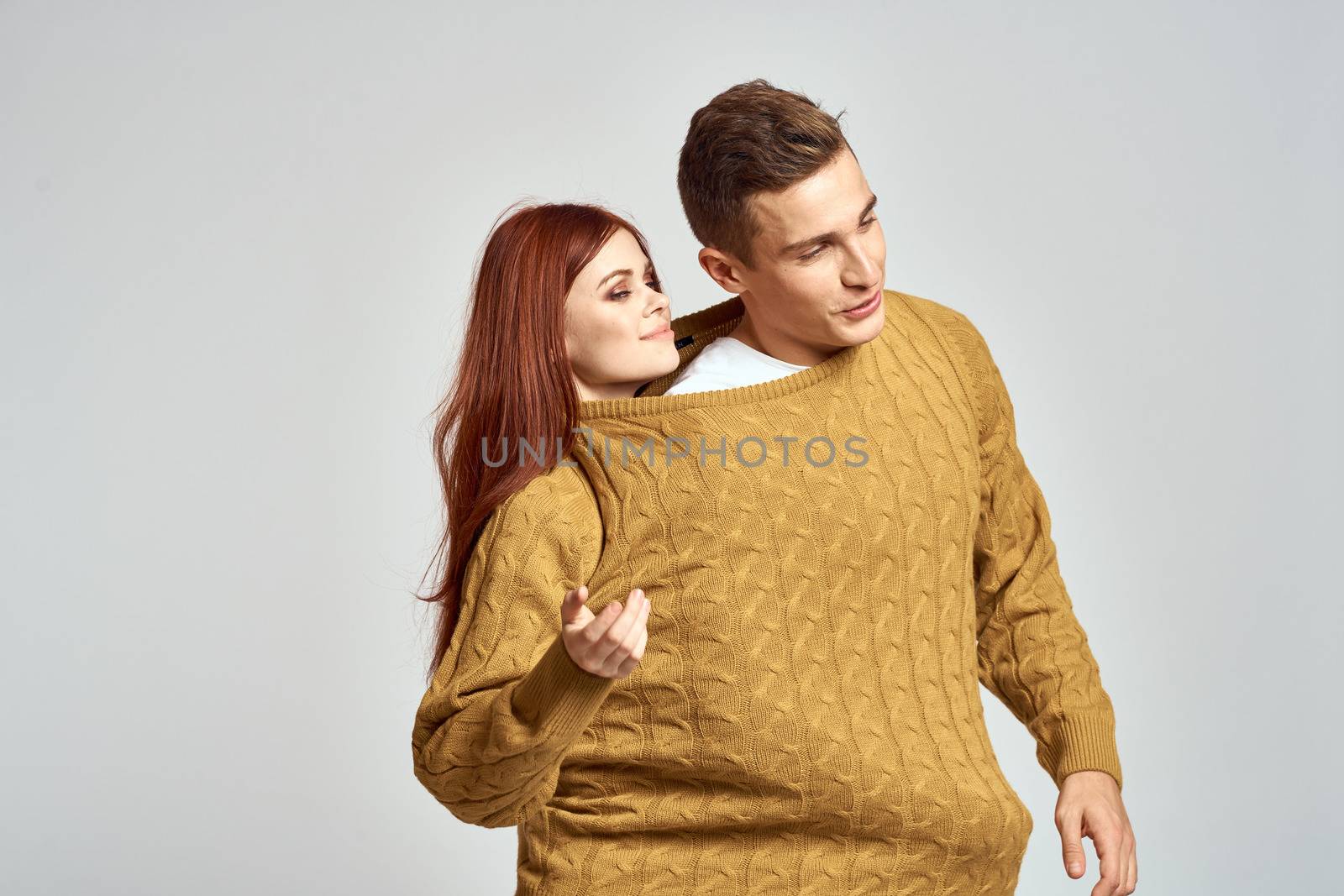 couple in yellow sweater posing against light background cropped view by SHOTPRIME