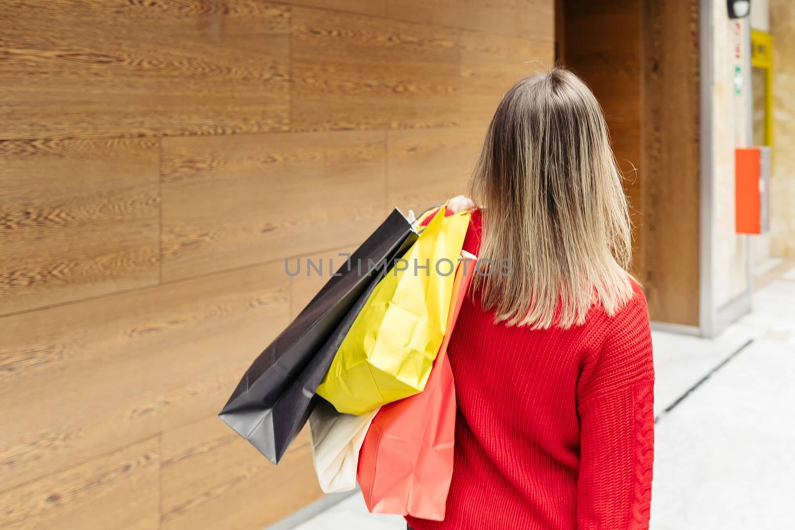 Adult woman walking through a mall with colorful shopping bags. Copy space.