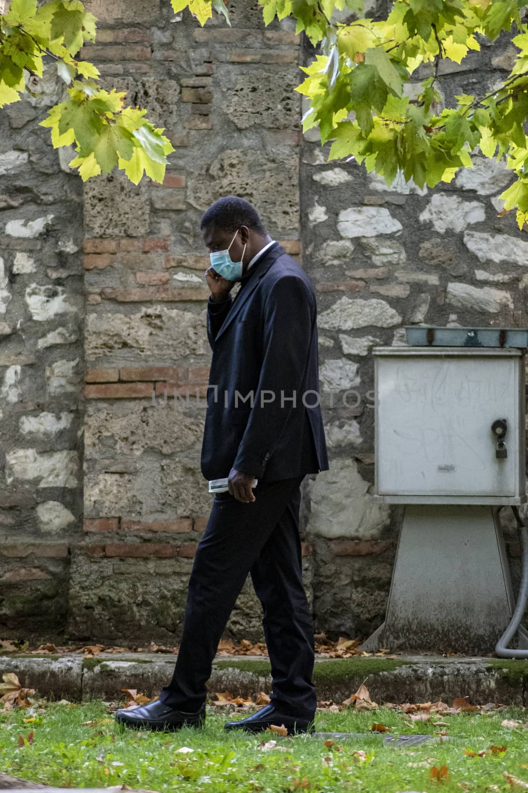 terni,italy october 19 2020:colored parish priest with medical mask and telephone