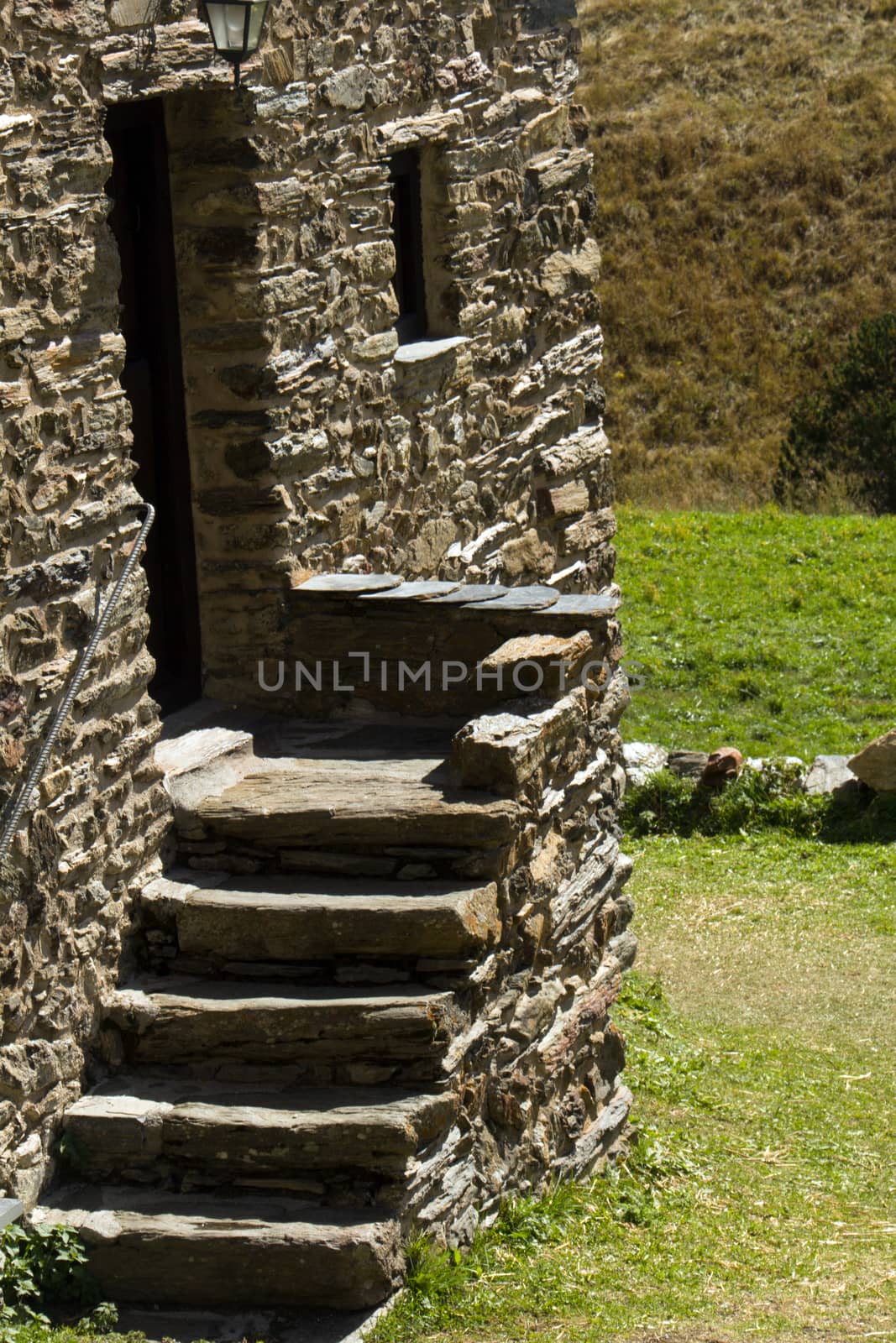 five stone stairs and entrance of an old village house and grass in the background