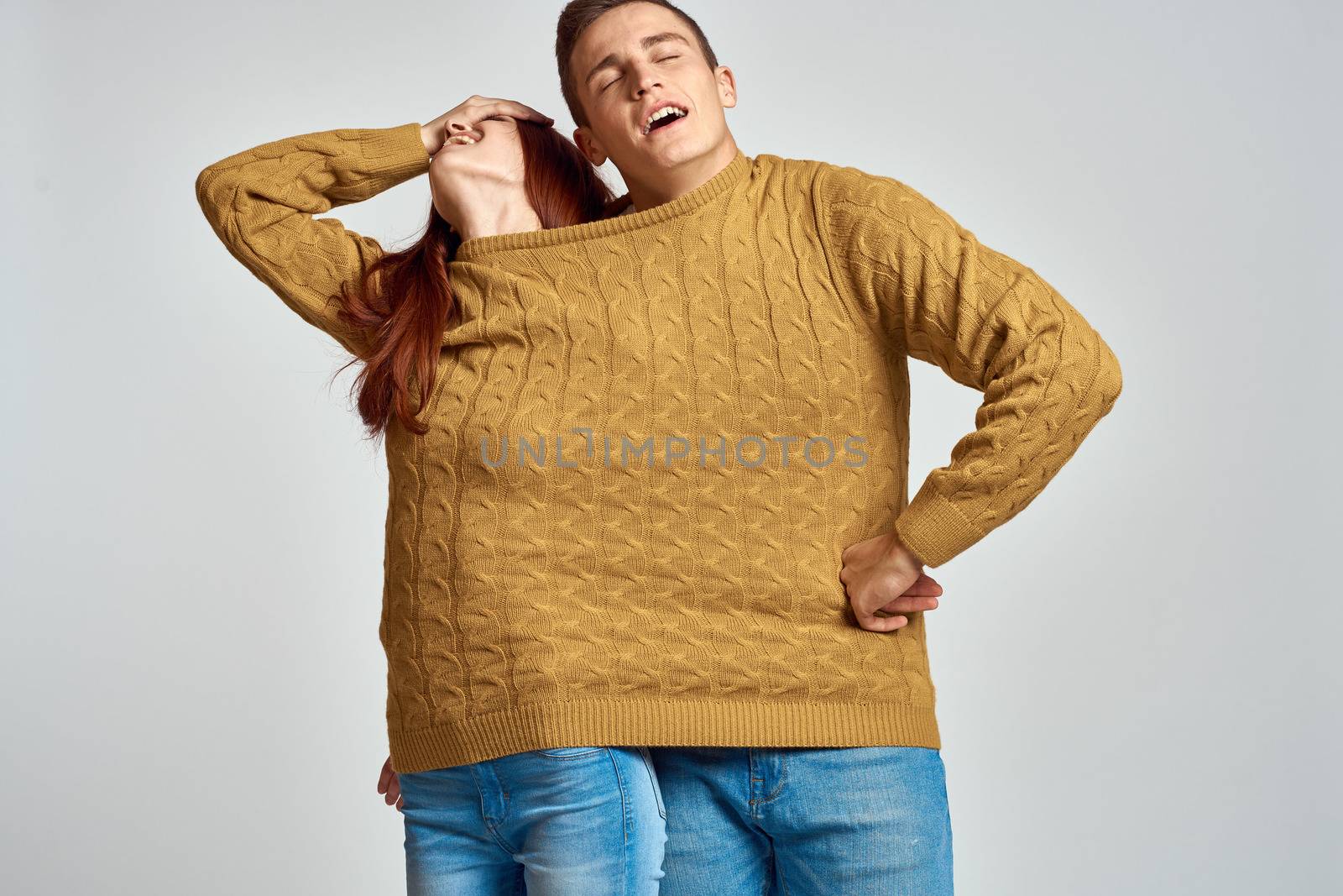 couple in yellow sweater posing against light background cropped view. High quality photo