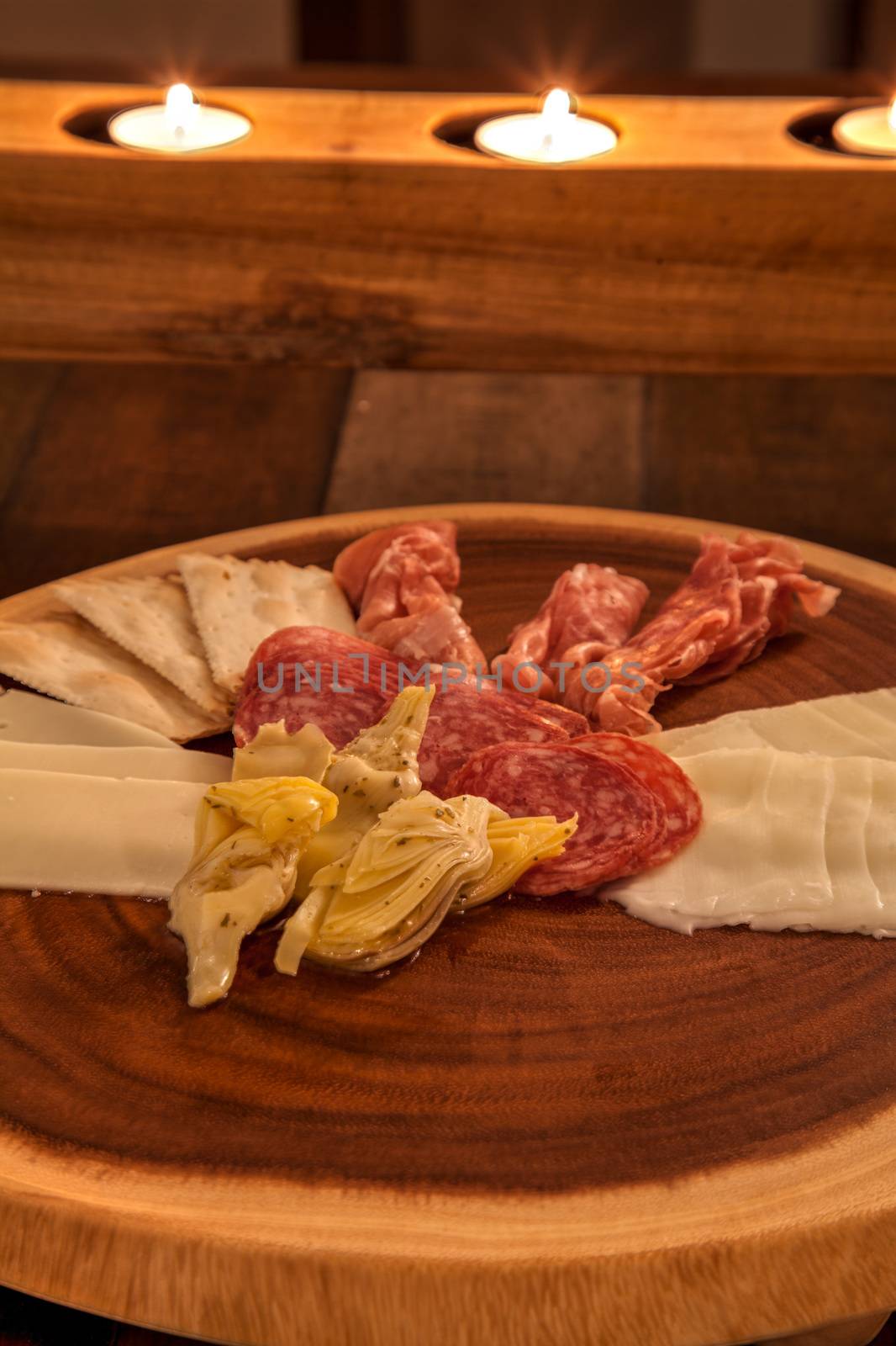 Charcuterie board on rustic wood with candles behind a spread of by steffstarr