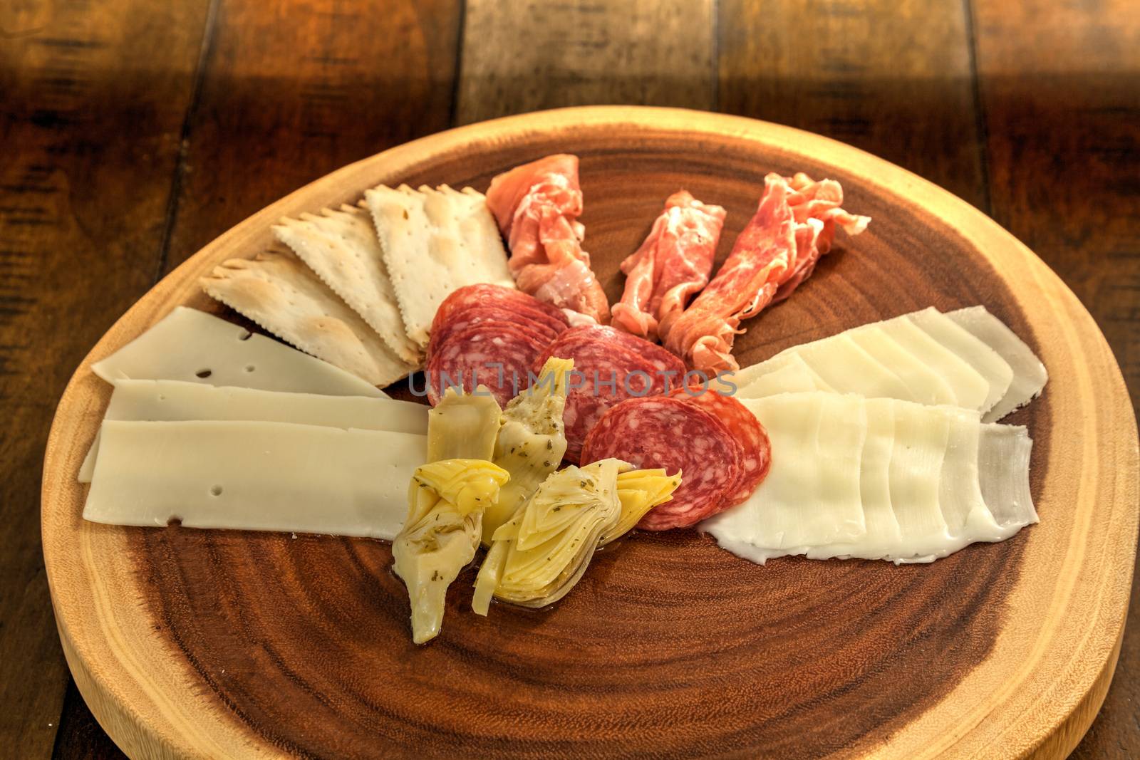 Charcuterie board on rustic wood with candles behind a spread of by steffstarr