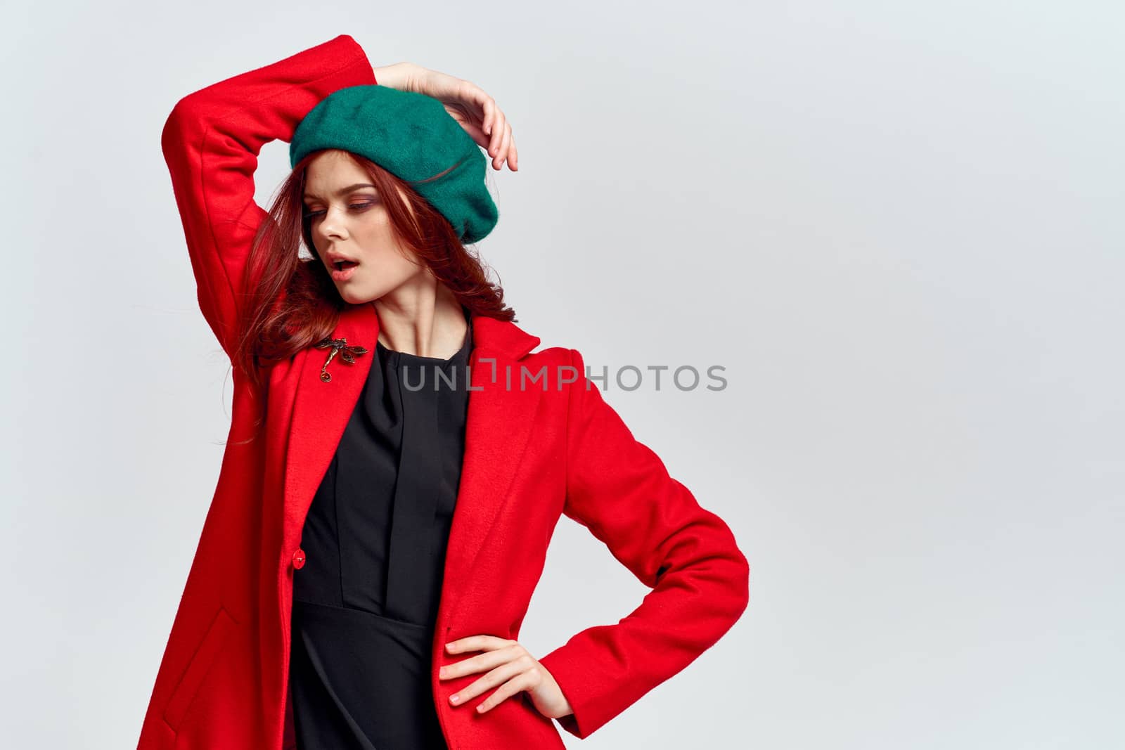 Woman in red coat and in green hat on isolated background cropped model with Copy Space emotions. High quality photo