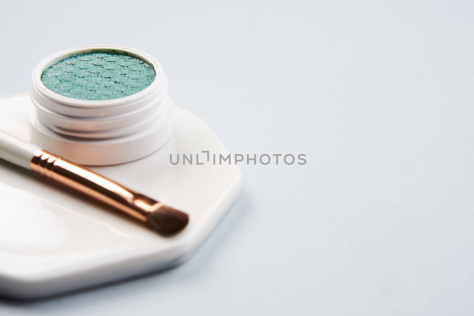 Green eyeshadow and makeup brush on white stand isolated background. High quality photo