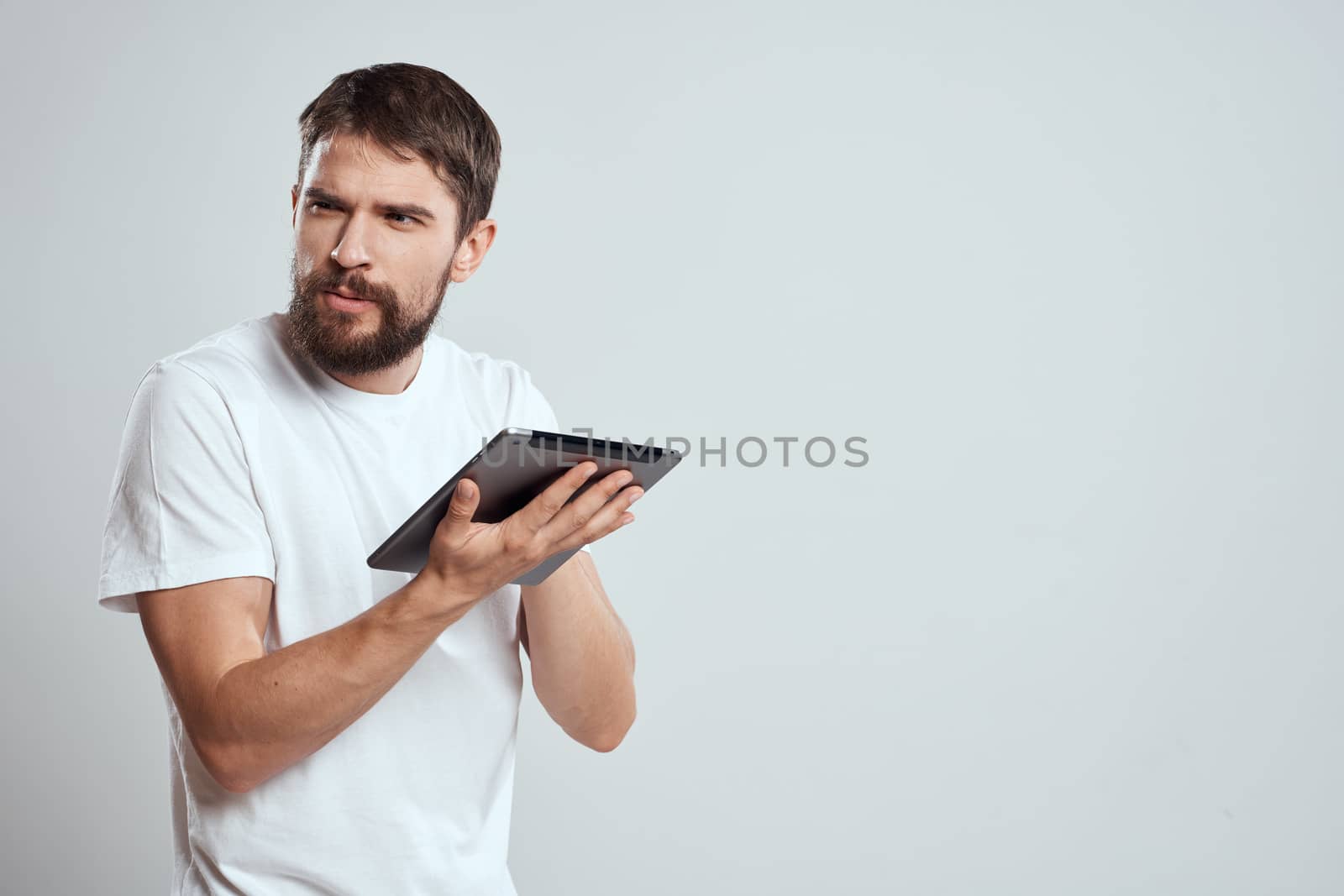 emotional man with tablet in hand touch screen new technologies light background cropped view Copy Space. High quality photo
