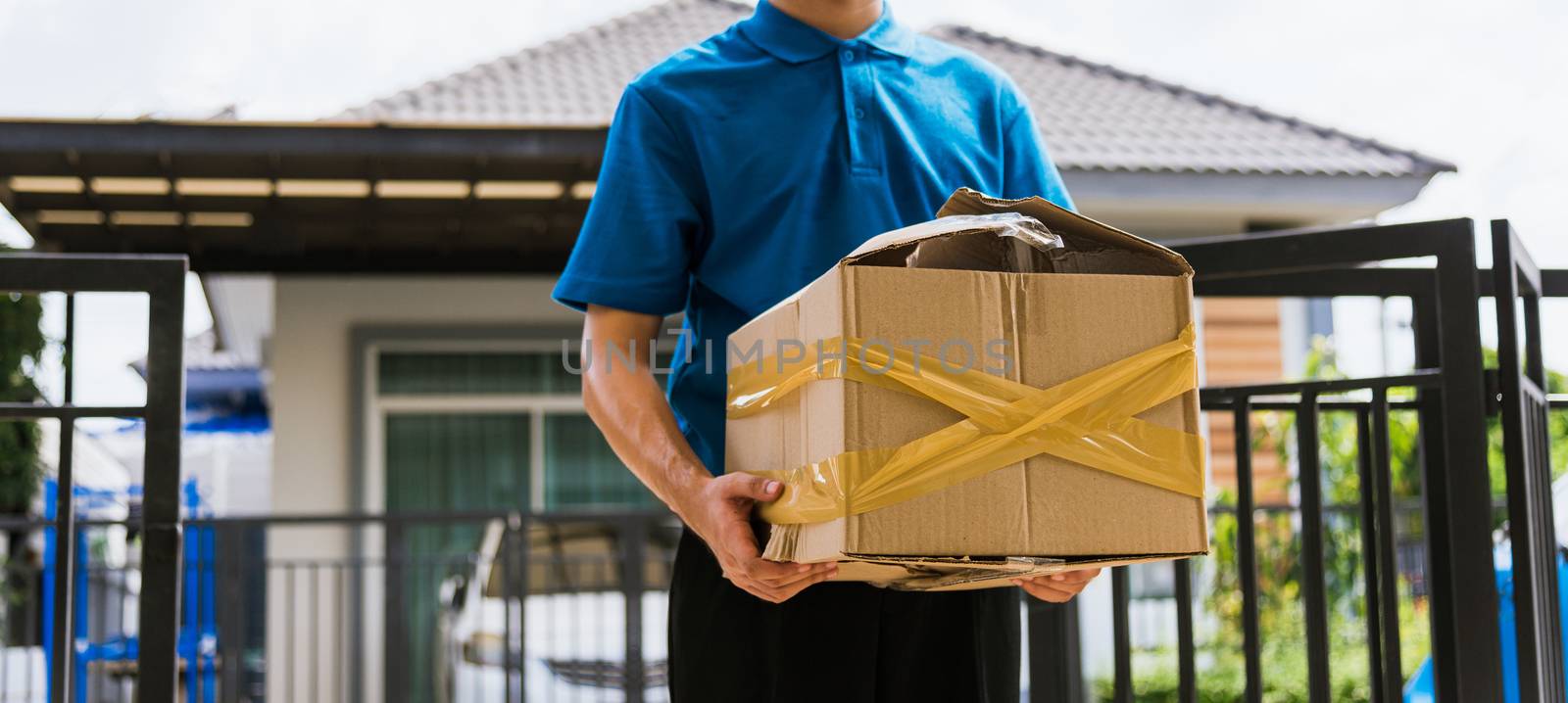 Asian young delivery man in blue uniform he emotional falling courier hold damaged cardboard box is broken at door front home, Accident bad transport shipment or poor quality delivery service concept