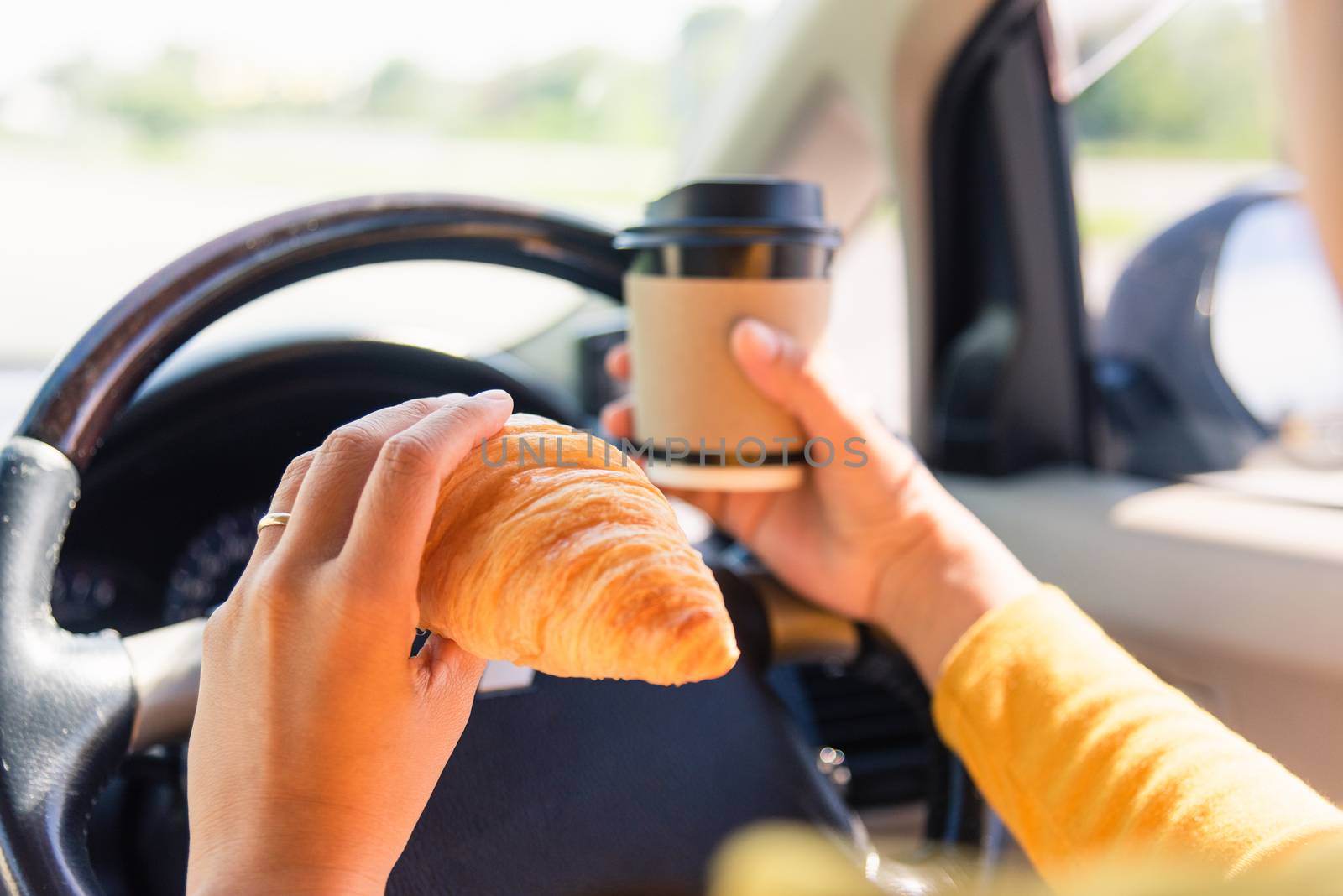 Asian woman eating food fastfood and drink coffee while driving the car in the morning during going to work on highway road, Transportation and vehicle concept