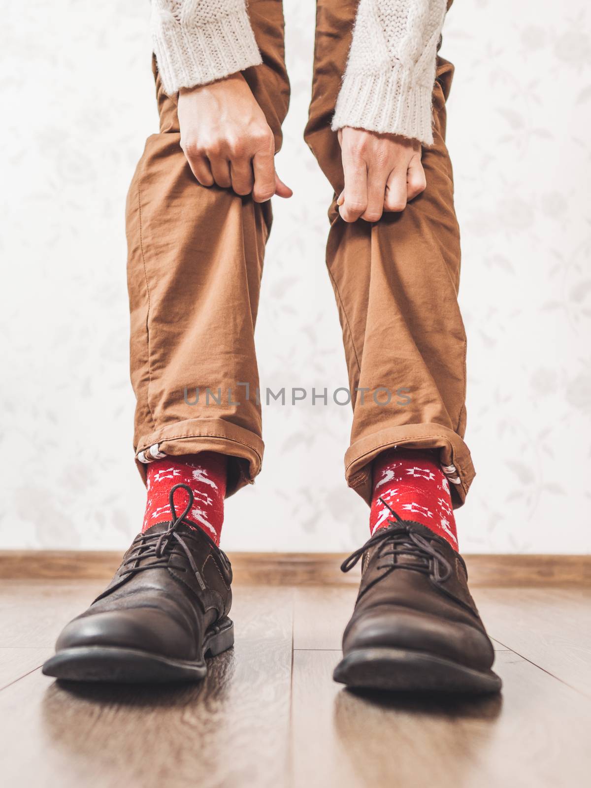 Young man pulls up leg of his chinos trousers to show bright red by aksenovko