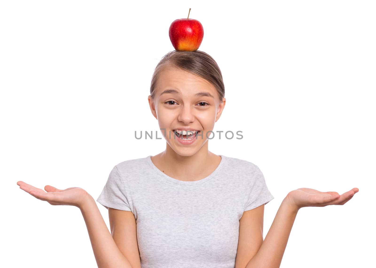 Happy beautiful young teen girl with apple on head, isolated on white background