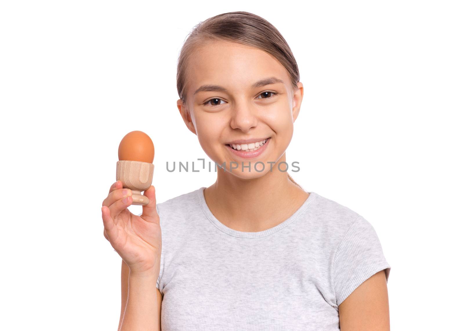 Portrait of beautiful young teen girl, holding boiled egg and spoon for breakfast, isolated on white background