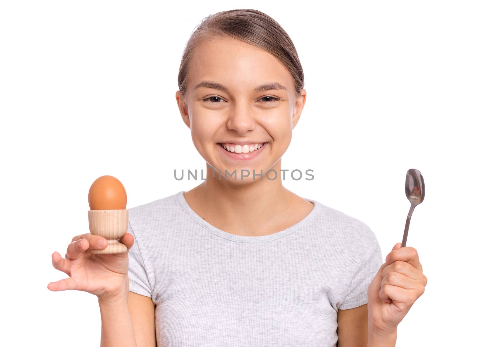 Portrait of beautiful young teen girl, holding boiled egg and spoon for breakfast, isolated on white background