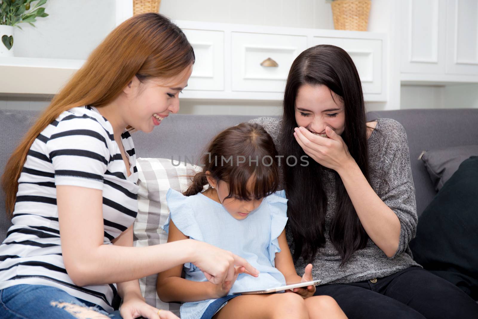 beautiful young mother, aunt and kid having time together with smile and happy learning on digital tablet in the living room at home, family activity concept.