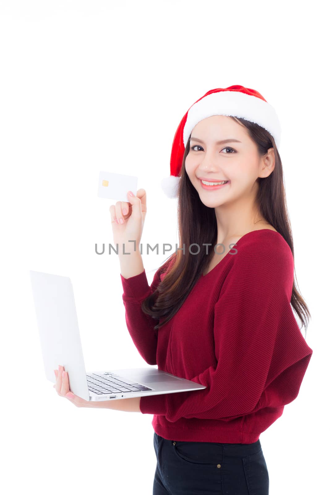 Portrait of beautiful asian young woman in santa hat using laptop computer and holding credit card isolated on a white background, shopping holiday concept.