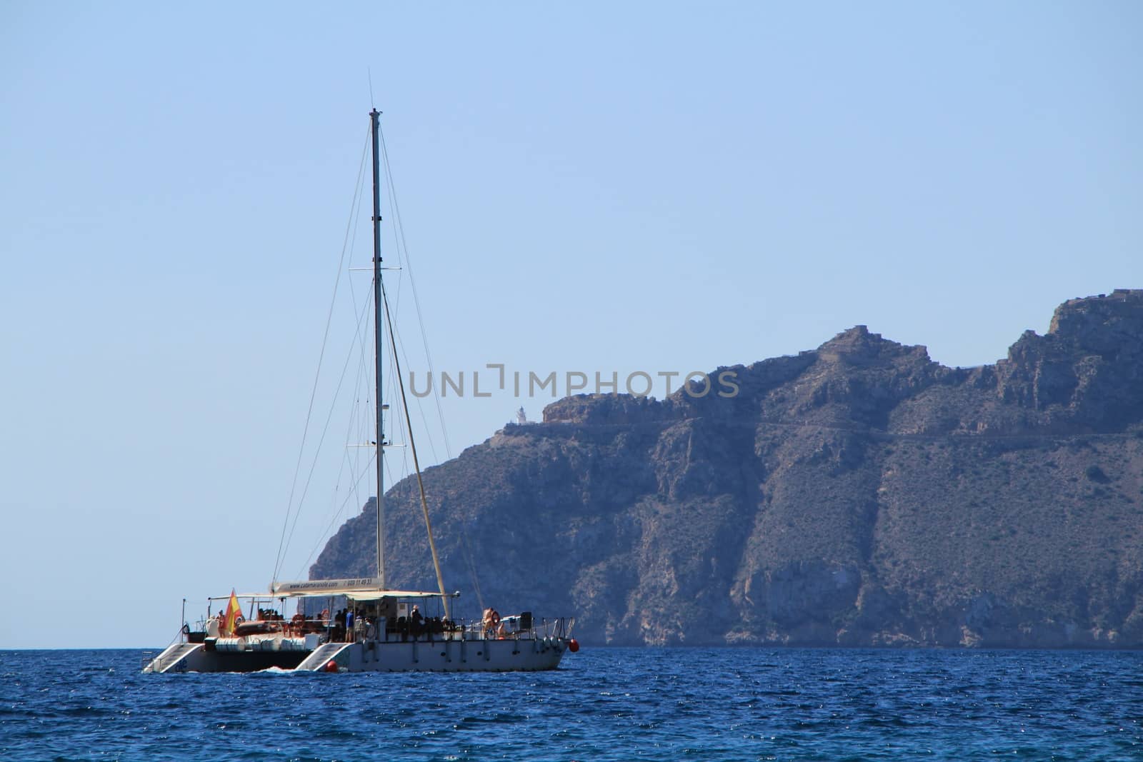 Mazarron, Murcia- October 2, 2019: Tourist catamaran full of tourists furrowing the coast in a sunny and clear day in Mazarron