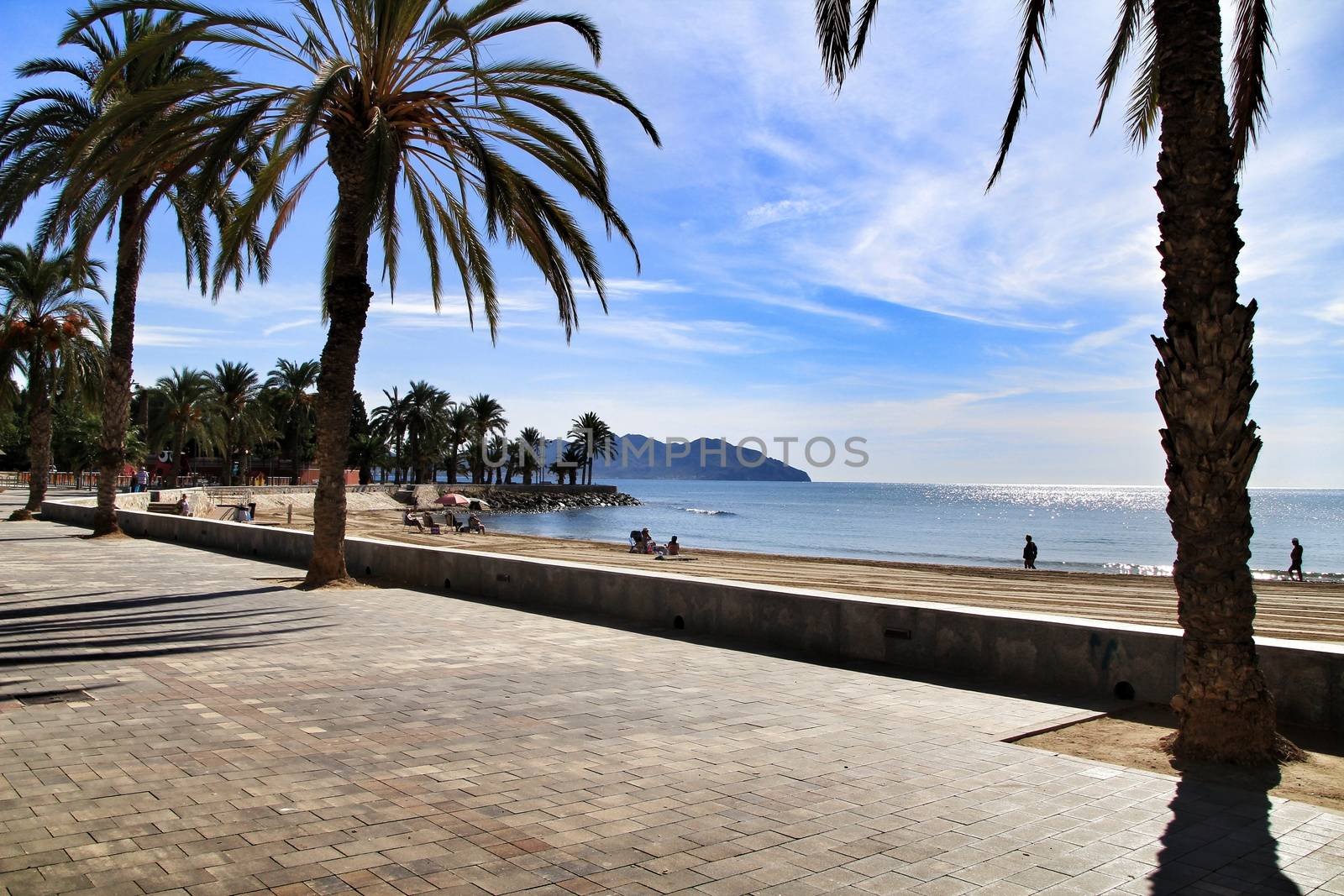 Mazarron, Murcia, Spain- October 3, 2019: Beautiful beach view from the promenade in a sunny and clear day in Mazarron, Murcia, Spain. People relaxing and sunbathing on the beach.