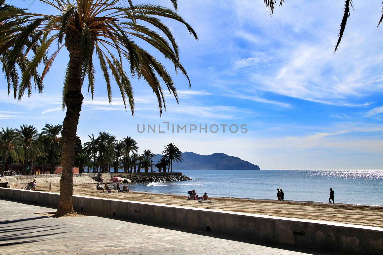 Mazarron, Murcia, Spain- October 3, 2019: Beautiful beach view from the promenade in a sunny and clear day in Mazarron, Murcia, Spain. People relaxing and sunbathing on the beach.