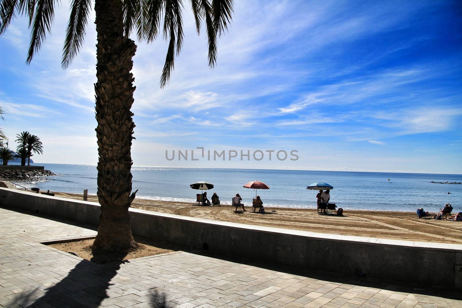 Mazarron, Murcia, Spain- October 3, 2019: Beautiful beach view from the promenade in a sunny and clear day in Mazarron, Murcia, Spain. People relaxing and sunbathing on the beach.