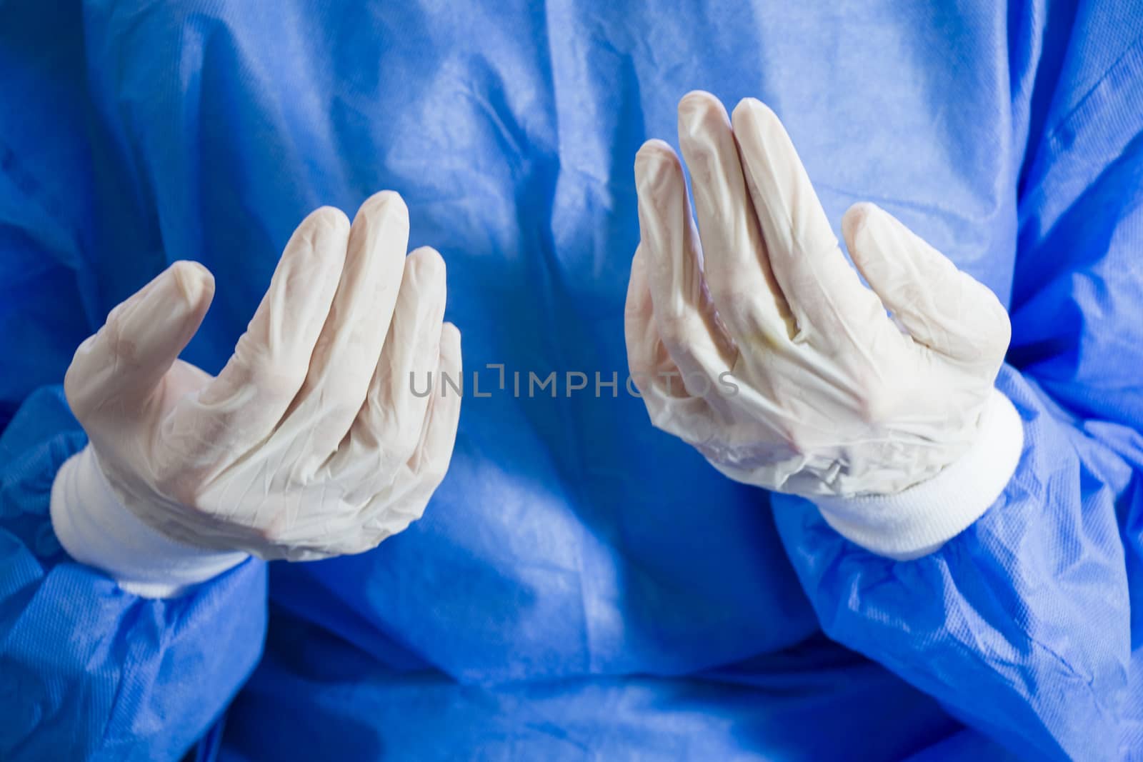 Doctors hands with sterile and disinfection white gloves close-up. Surgery and nurse uniform. Blue background.