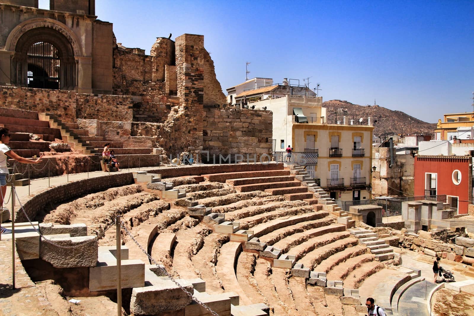 Cartagena, Murcia, Spain- July 25, 2019: Tourists visiting Archeological remains of the roman amphitheater of Cartagena in a sunny day of summer.