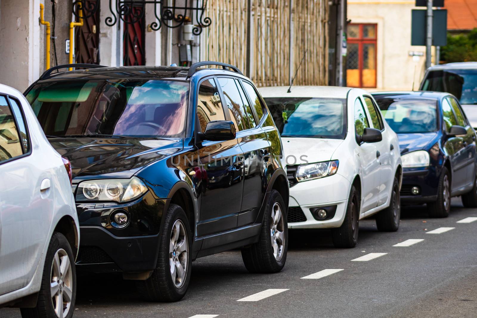 Parked cars along a street in Bucharest, Romania, 2020. by vladispas