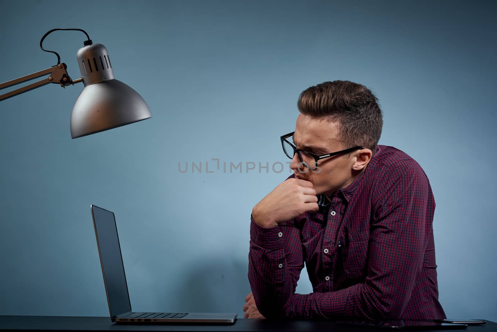 A man in a shirt with a laptop at the table is a manager in the office and a lamp cabinet model. High quality photo