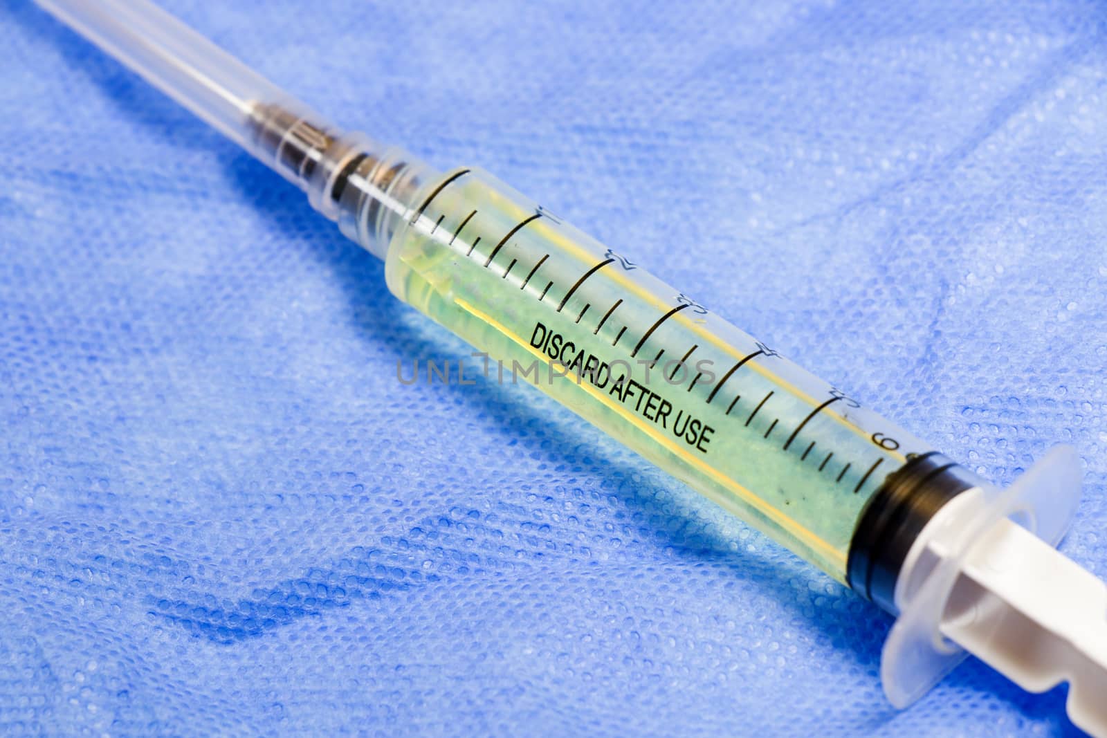 Medical needle on the sterile table with liquid vaccine, yellow vaccine for viruses. Vaccination and antibiotics. Studio shoot.