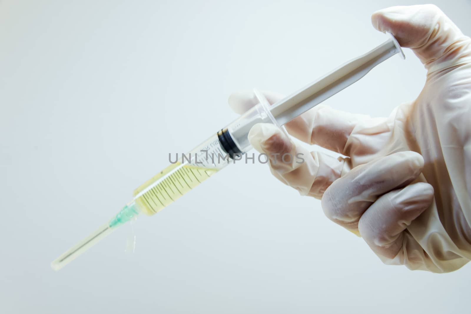 Medical needle and doctors hand with glove on the white background, corona virus or covid-19 vaccine in needle. by Taidundua