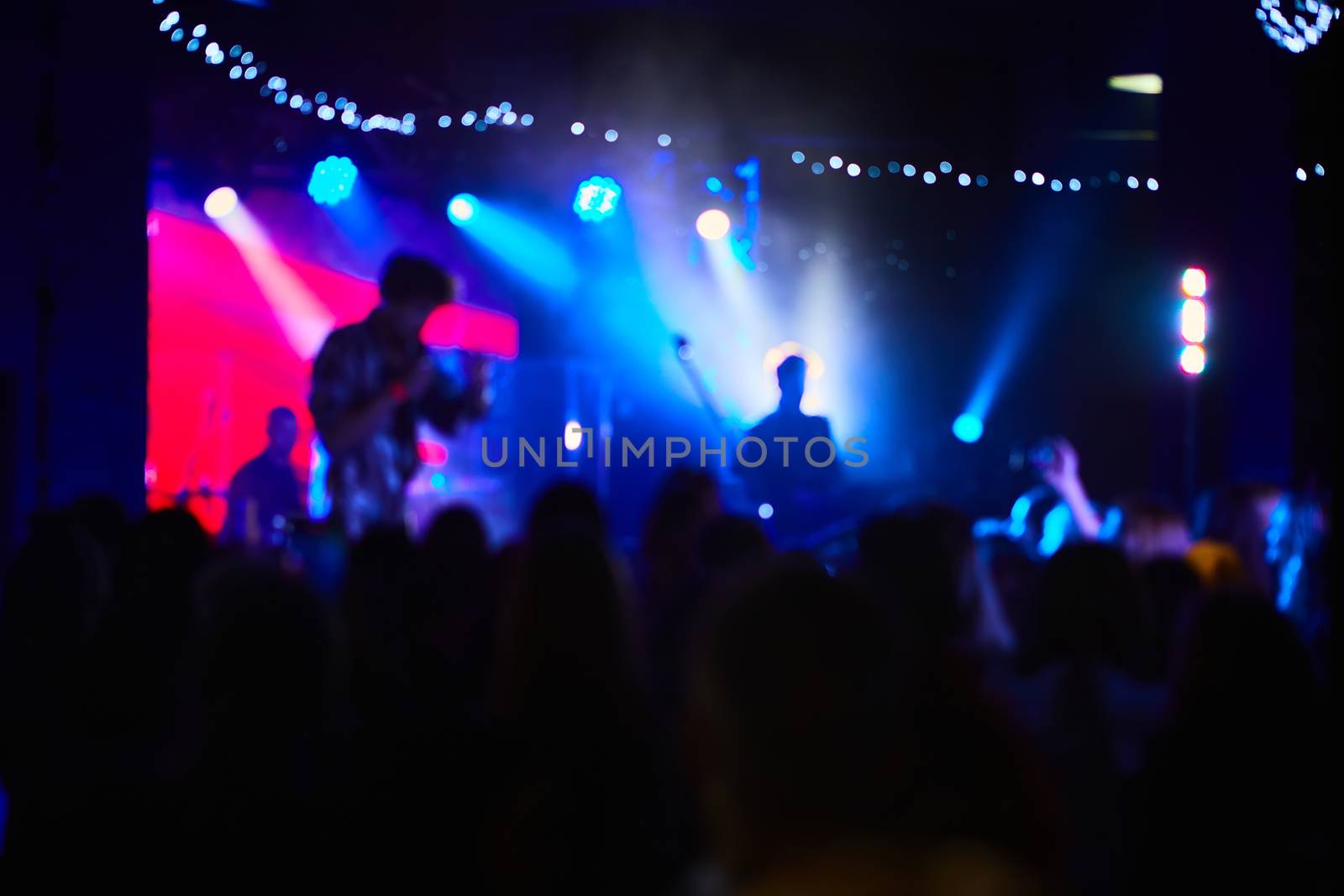 Music Concert background blur. Blurred People dancing with original bokeh lights in background - Defocused image for an artistic touch of disco club - Concept of nightlife with music and entertainment - Original lights colors