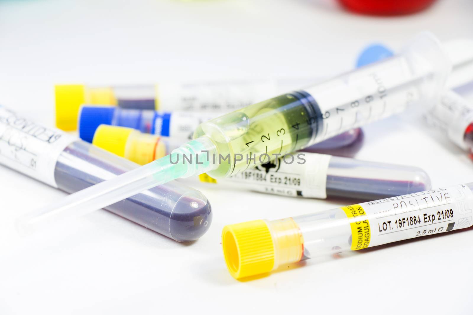 Corona virus and Covid-19 positive blood test tubes on the white background. Diagnosis and laboratory. Medical needle and blood tube, corona virus or covid-19 vaccine. Close-up and studio shoot.