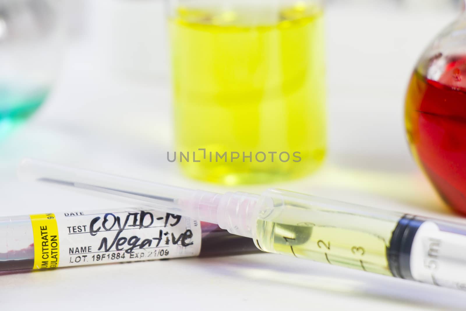 Corona virus and Covid-19 positive blood test tubes on the white background. Diagnosis and laboratory. Medical needle and blood tube, corona virus or covid-19 vaccine. Close-up and studio shoot.