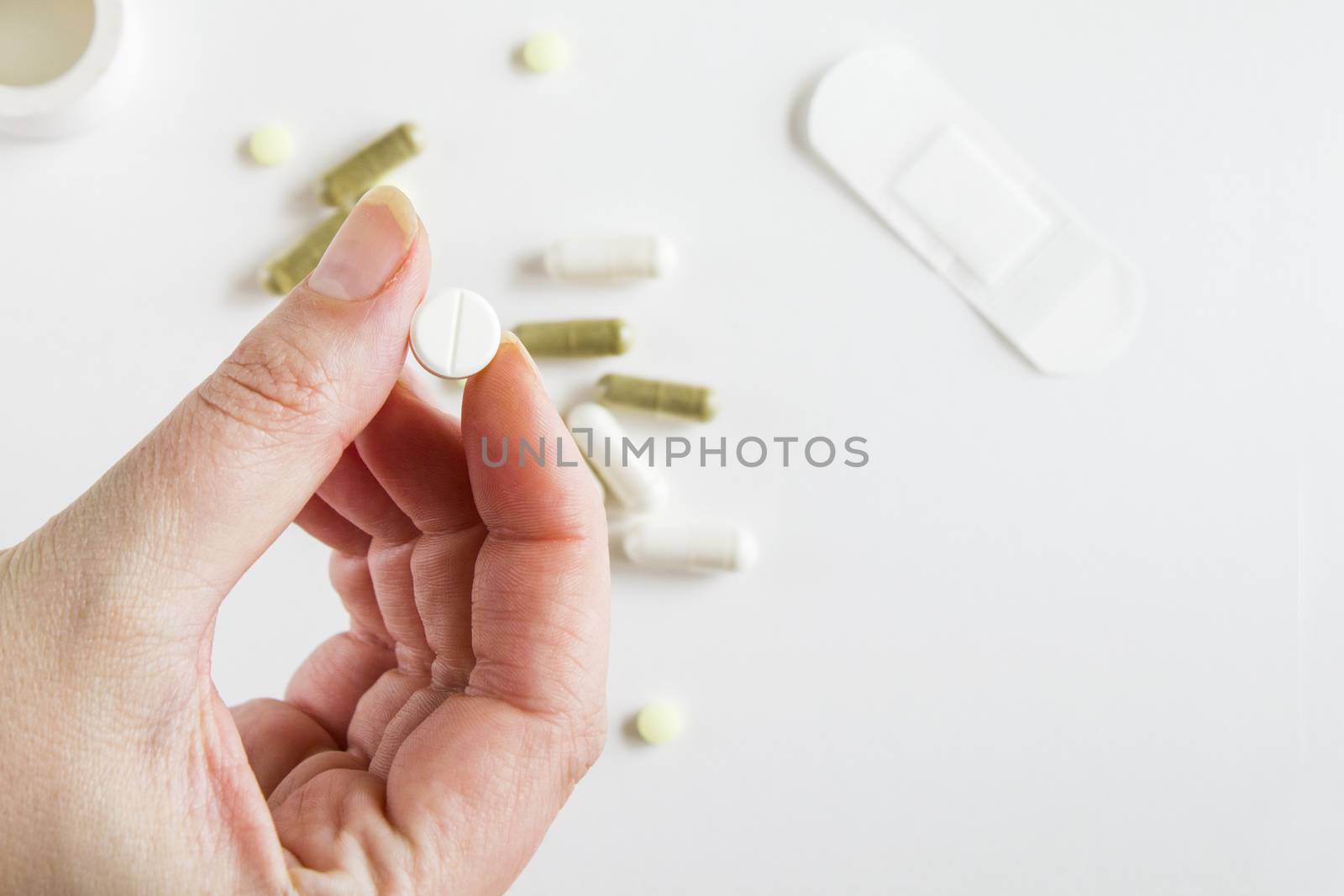 Drugs and pills, medicine and healthy care. Human hand holding white pill, on the white background, studio shoot.