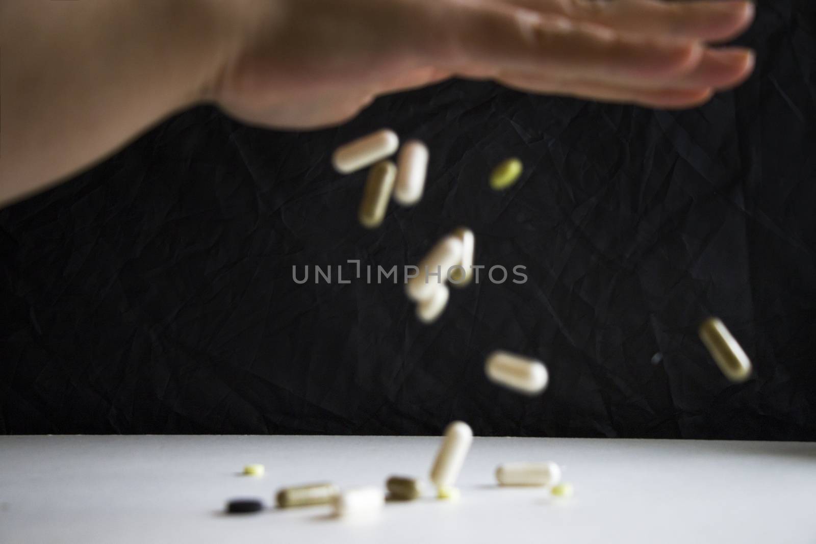 Drugs and pills, medicine and healthy care. Human hand holding white pill, on the black background. by Taidundua
