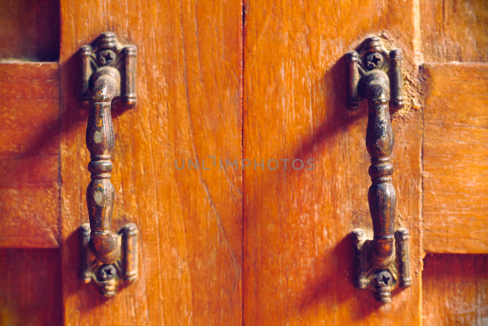 The vintage door handle on an old wooden door background and lighting and shadow in the morning. Closeup and copy space on the centred. The concept of art and architecture in vintage style.