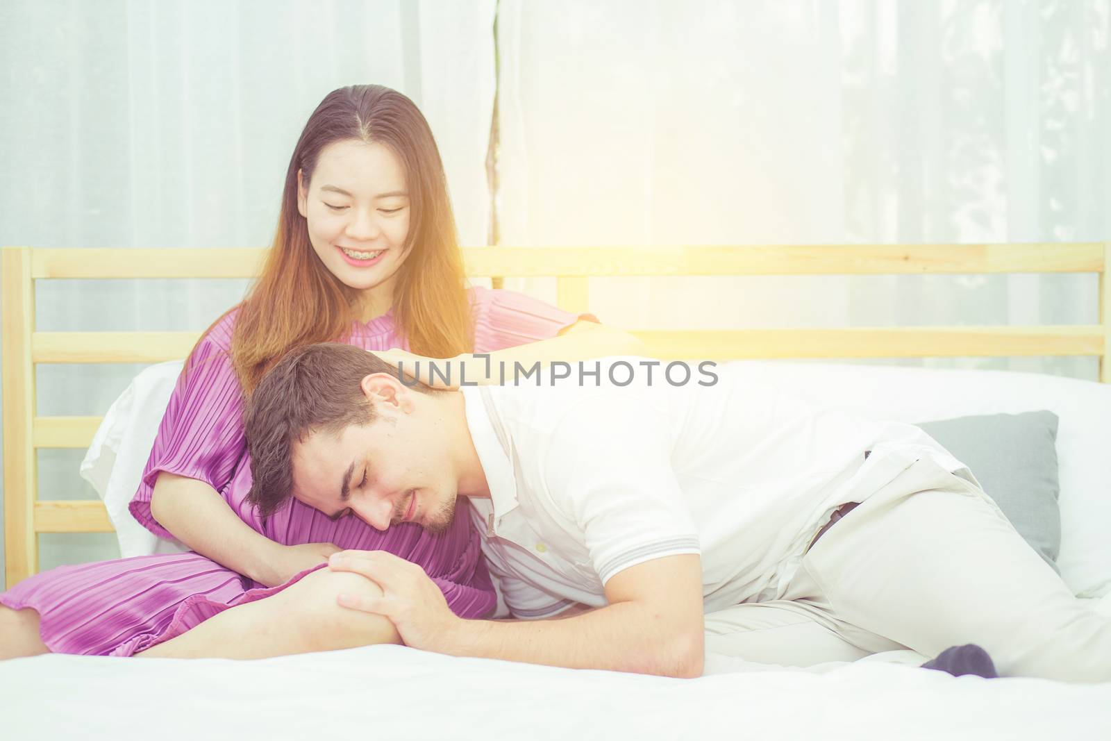 Beautiful pregnant asian woman and husband listening to baby with belly in bedroom with happiness, family concept.