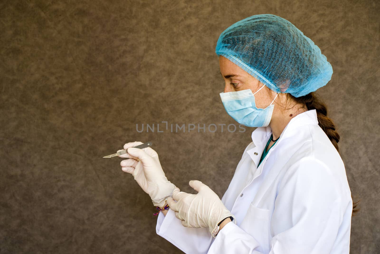 Woman doctors portrait, doctors with mask, glove and uniform and surgery blade in hand. by Taidundua