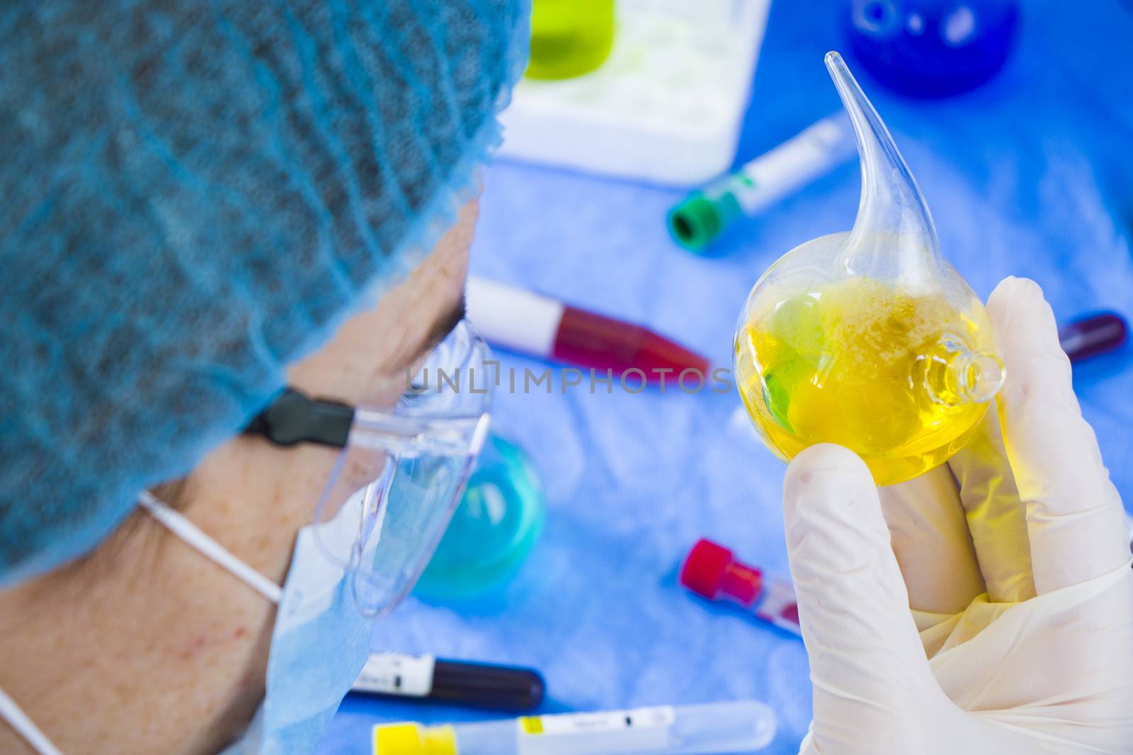 Doctors in uniform, face mask and glasses looking at sample in laboratory, colorful liquid chemical elements, research diagnoses