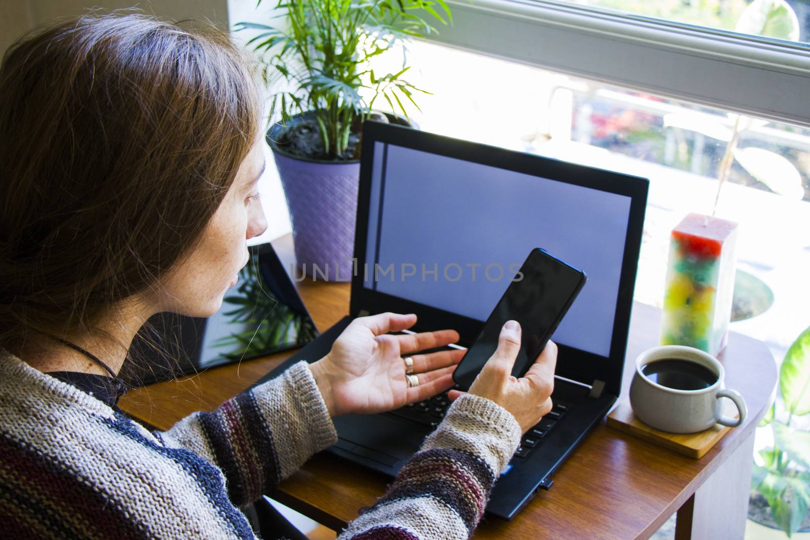 Woman working with notebook in workplace, digital tablet, mobile phone, coffee and plants in workspace, home working