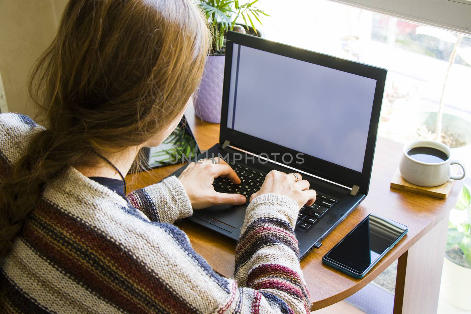 Woman working with notebook in workplace, digital tablet, mobile phone, coffee and plants in workspace, home working