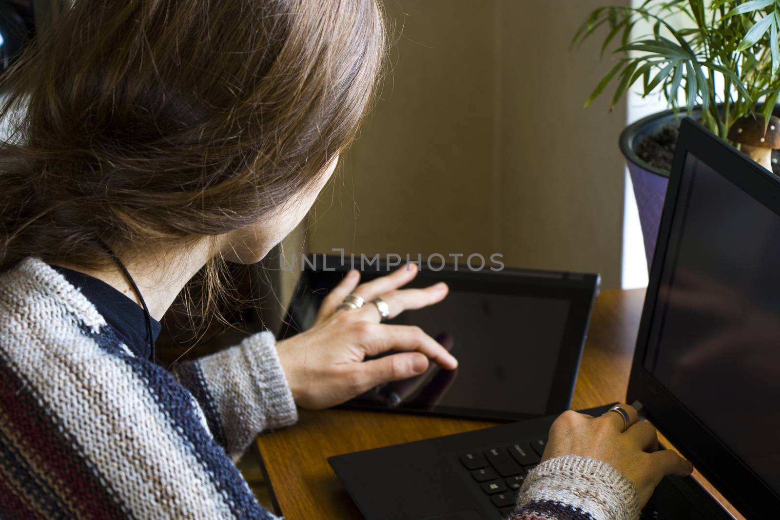 Woman working with notebook in workplace, digital tablet, mobile phone, coffee and plants by Taidundua