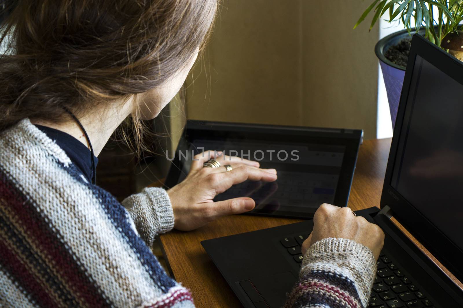 Woman working with notebook in workplace, digital tablet, mobile phone, coffee and plants by Taidundua