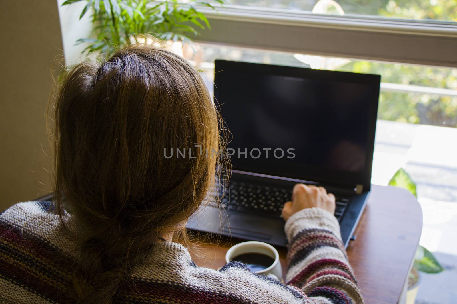 Woman working with notebook in workplace, digital tablet, mobile phone, coffee and plants in workspace, home working